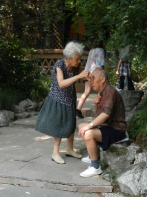 A woman gives her husband a haircut in the park in Shanghai